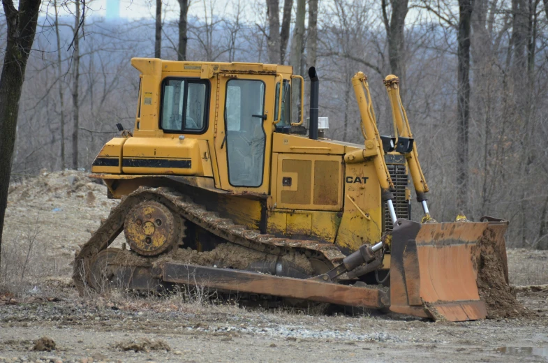 an abandoned bulldozer in the dirt with a dusting blade