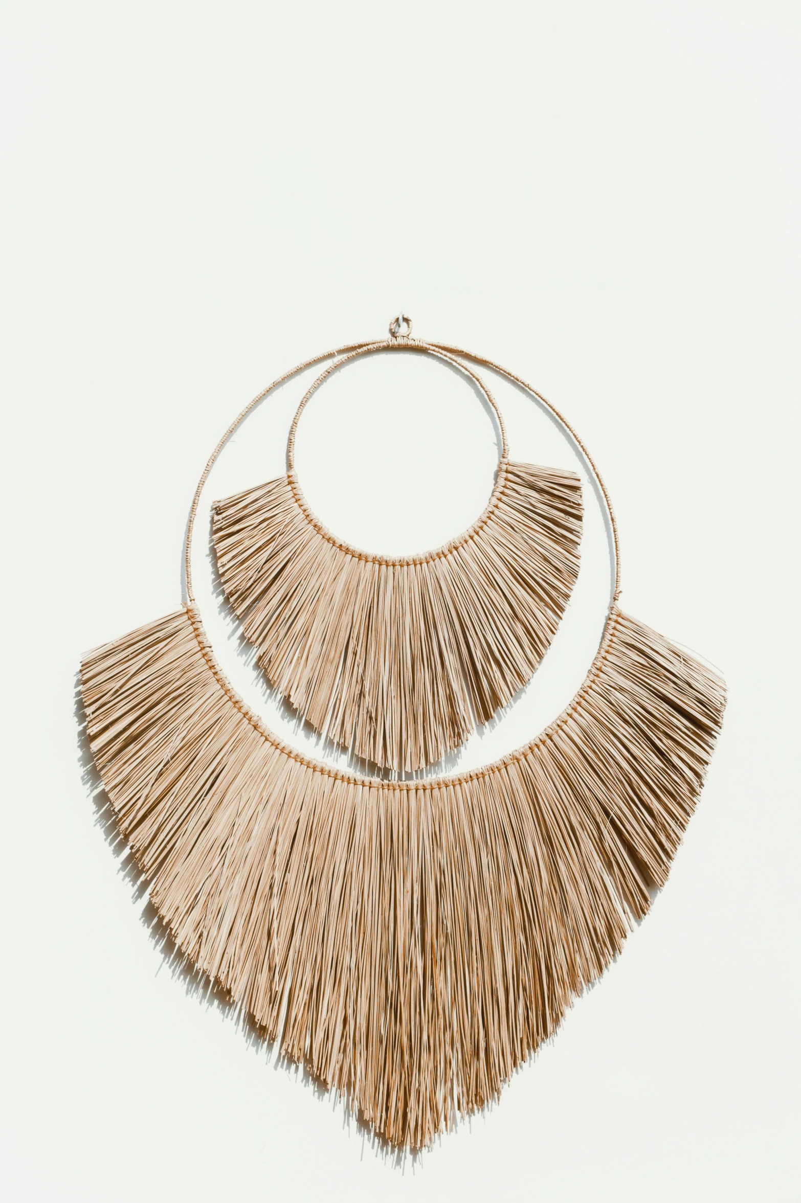 two woven fan shaped earrings sitting on top of each other