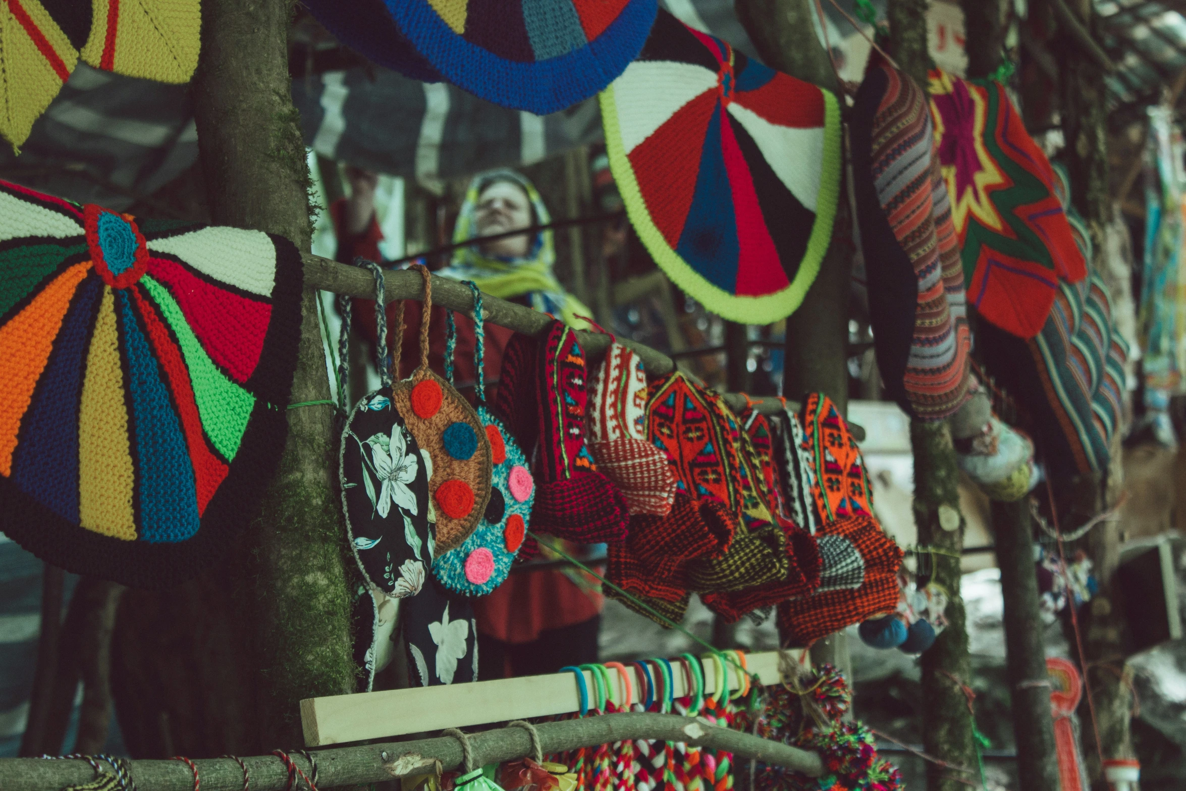 colorful hats are hanging from a rack and on the pole