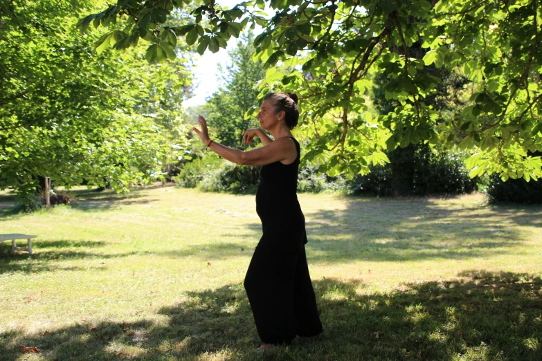 a woman in black dress blowing bubbles while standing under tree