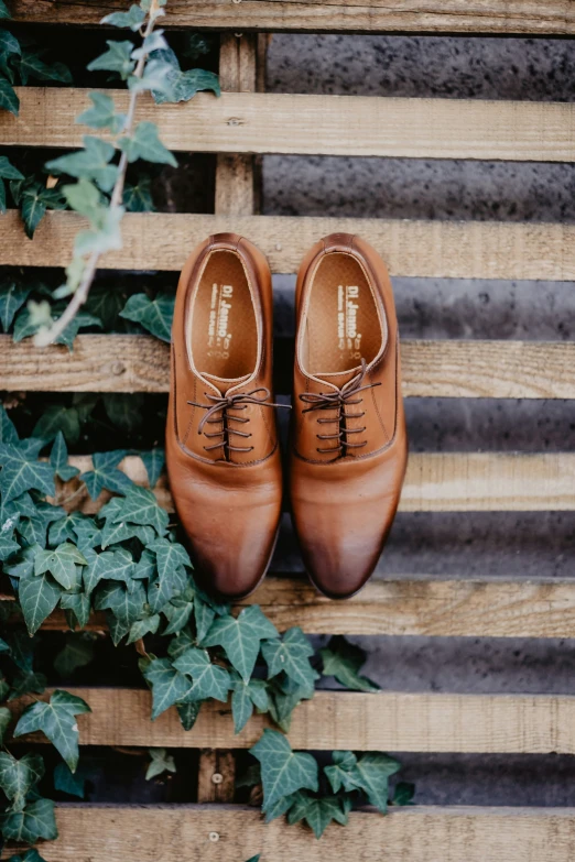 a pair of brown shoes sits on top of a wooden bench