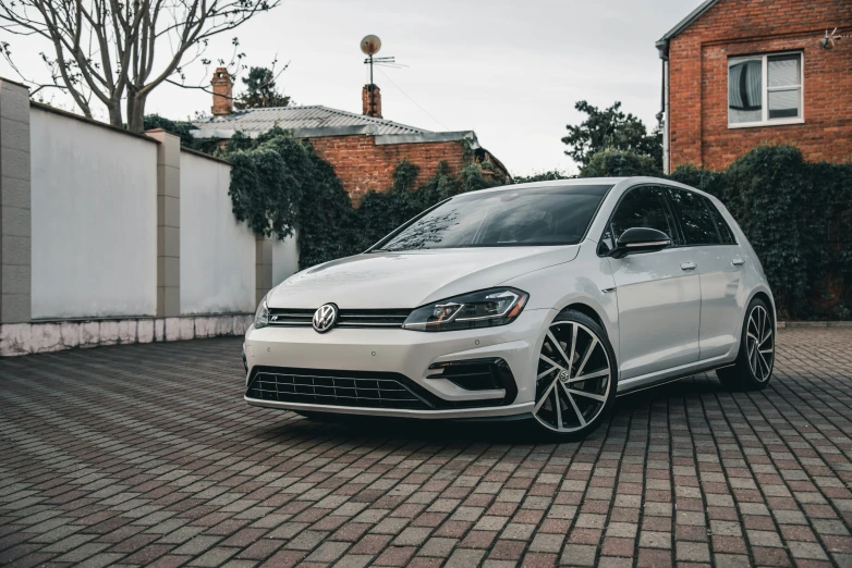 a white car parked on top of a stone paved driveway