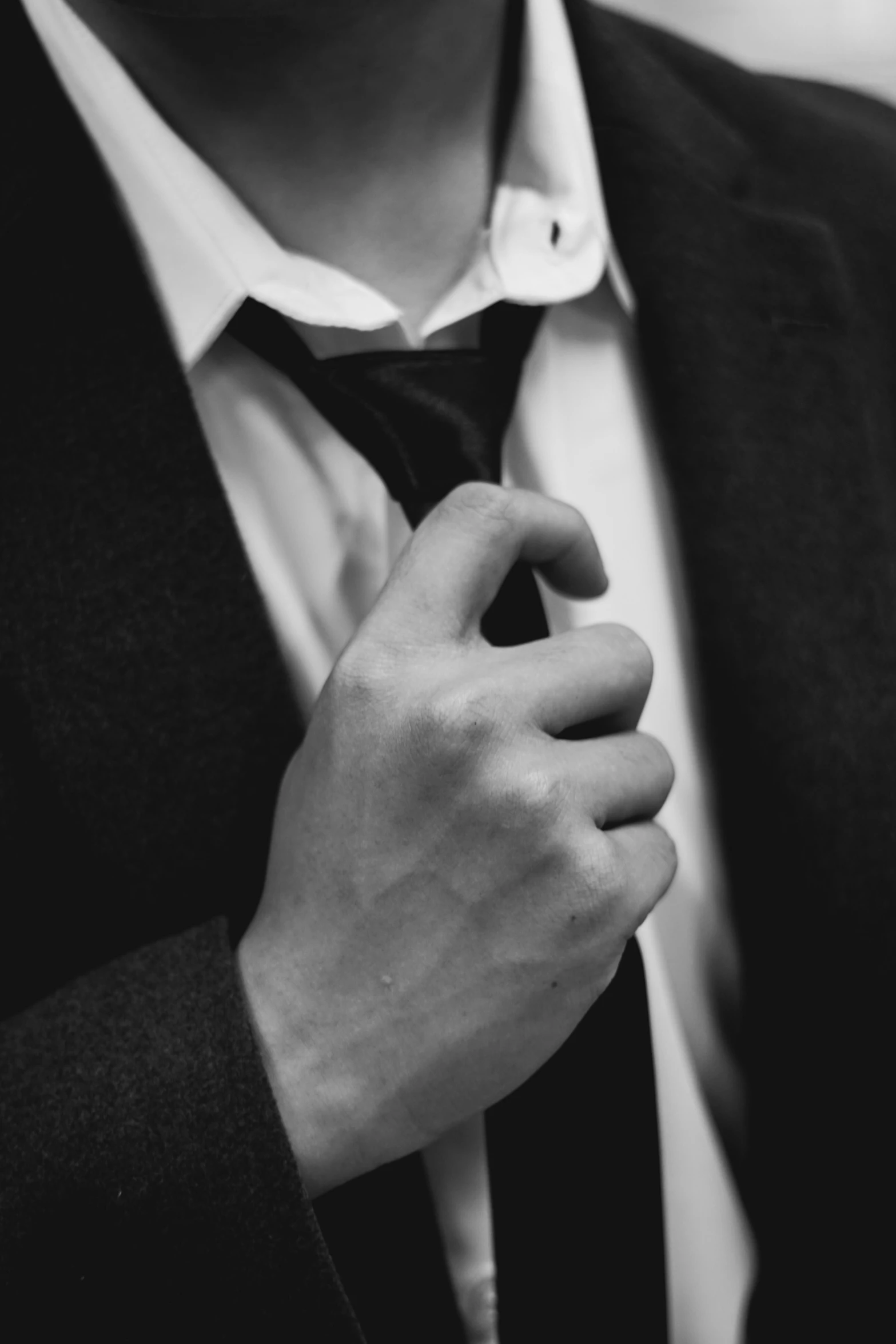 man's hands adjusting the tie of his suit coat