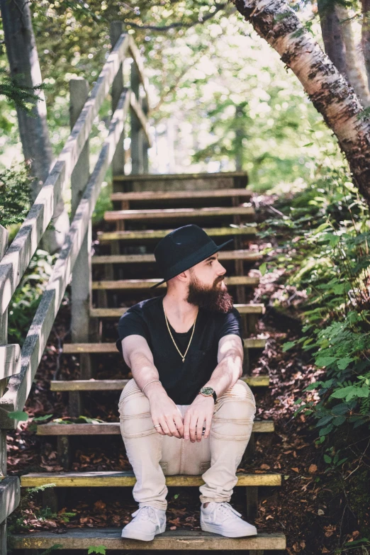 a bearded man is sitting on a set of stairs