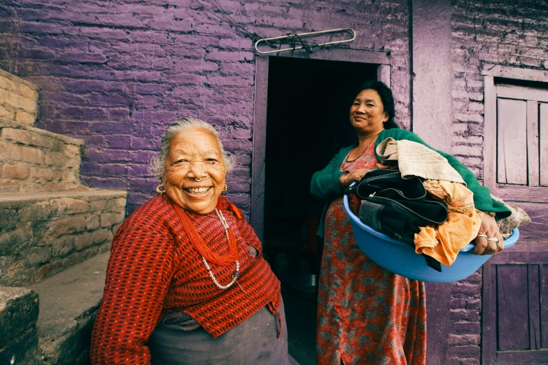 a woman in a red shirt and a older women with a bucket