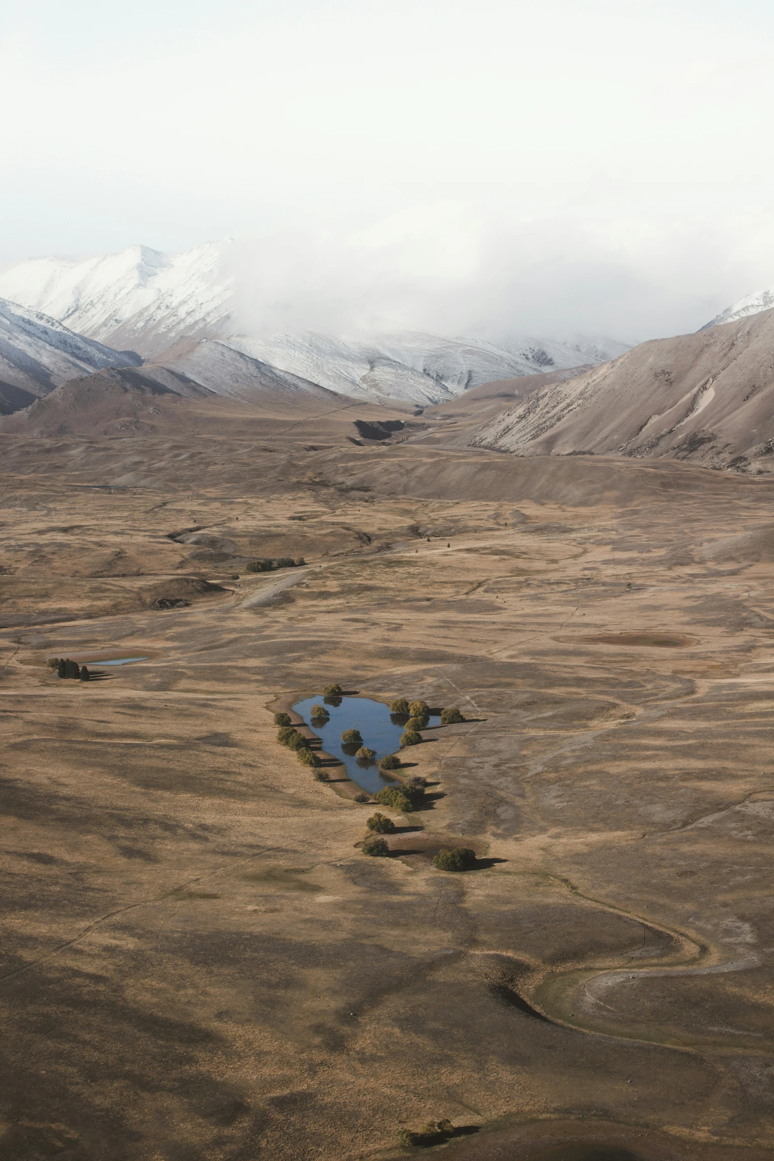 a dirt field with snow covered mountains in the background