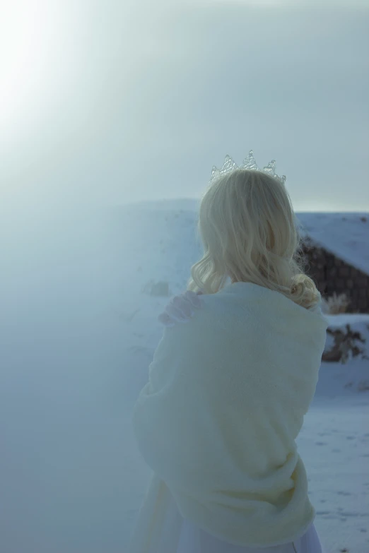 a girl standing in the snow wearing a tiara