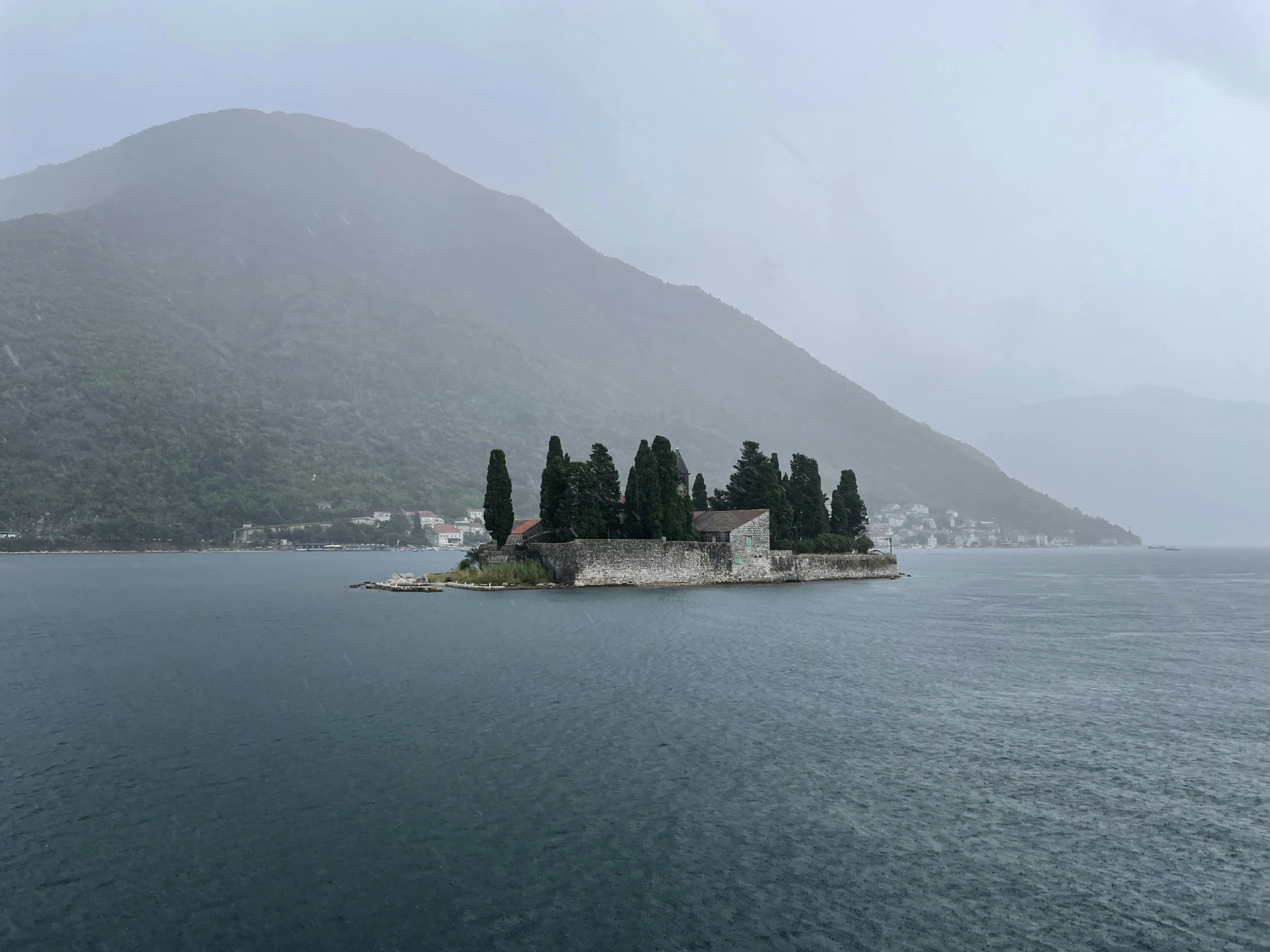 an island sitting in the middle of water with a mountain in the background