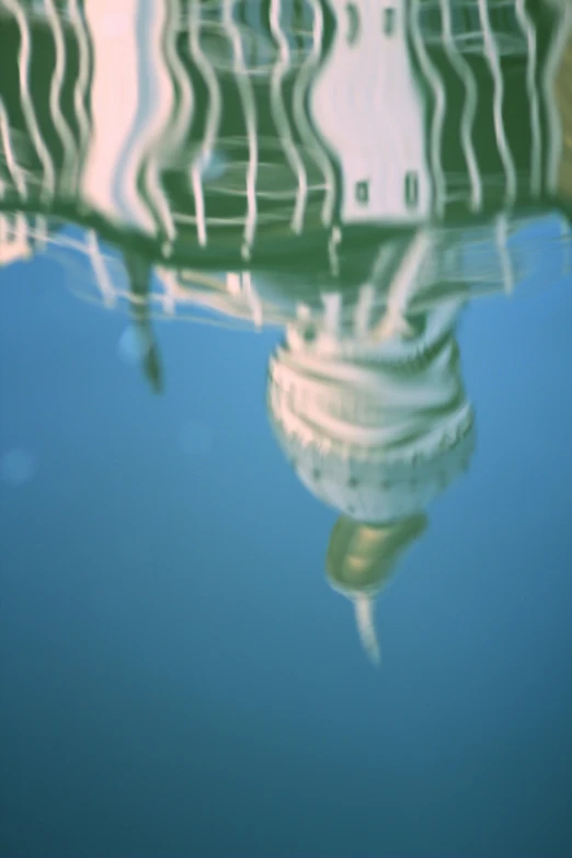 a building reflected in the water by the reflection of the umbrella