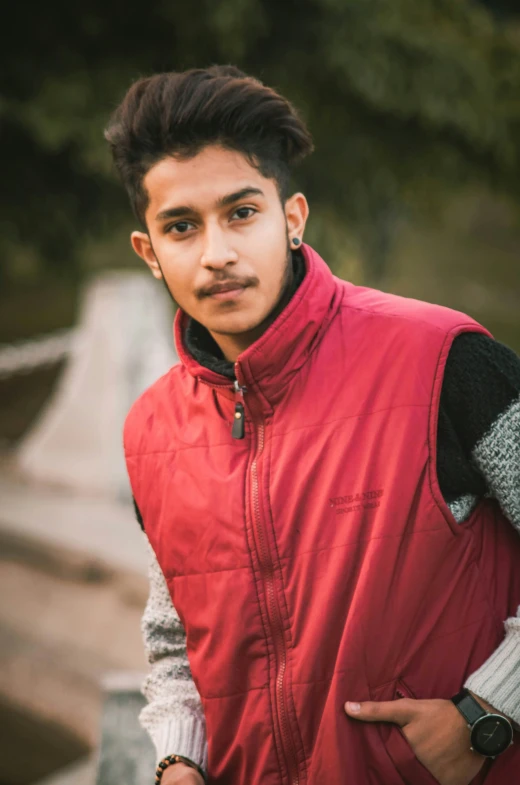 a man in a vest posing with his hands in his pockets