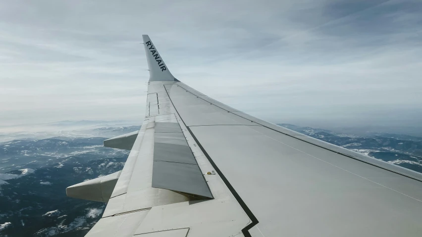 looking down at an airplane wing with mountains in the background