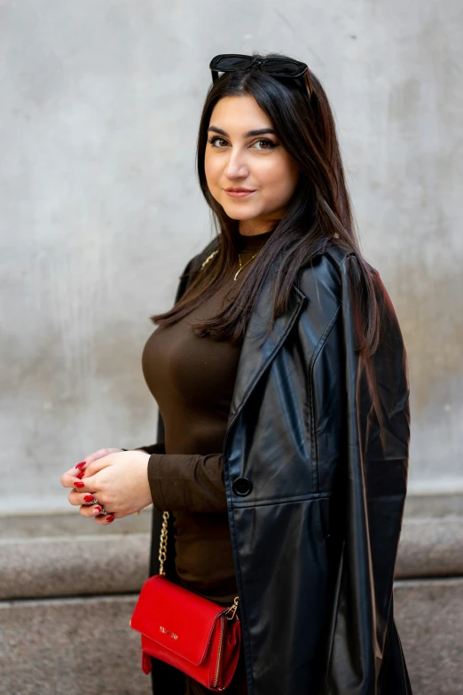 a woman with her handbag standing next to a wall