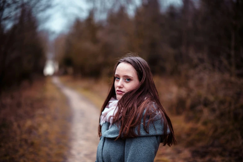 a woman is standing by a dirt road