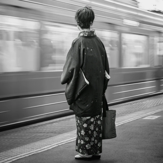 a person in an asian kimono stands at a train station