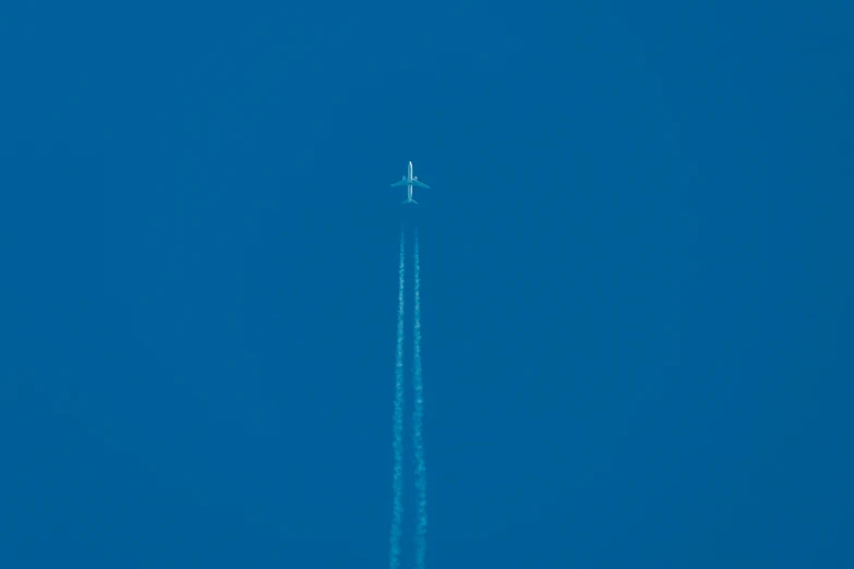 an airplane in the sky leaving a trail behind