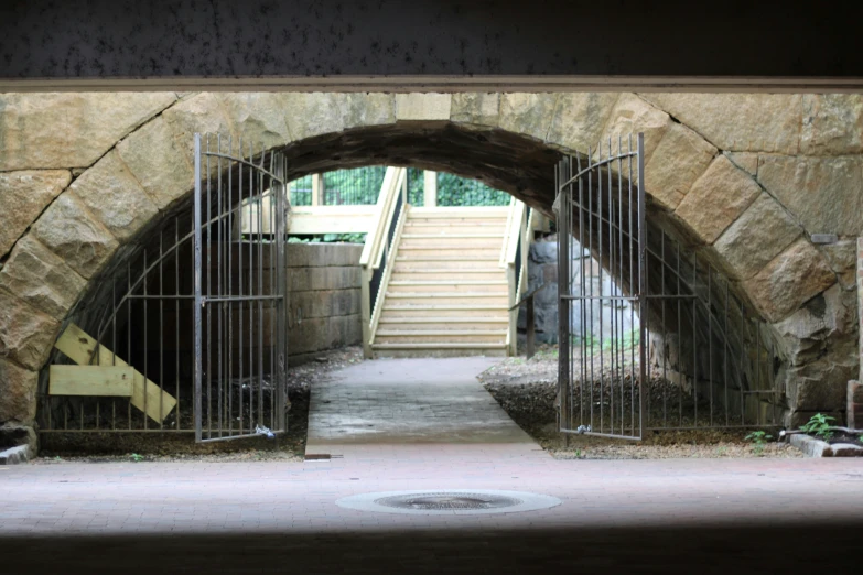 an arch shaped building has iron gates with stairs