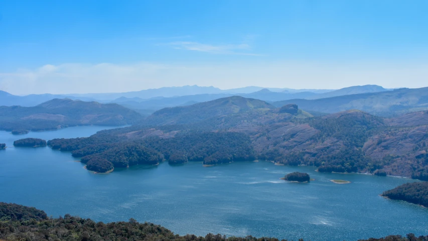 many large mountains are behind a lake