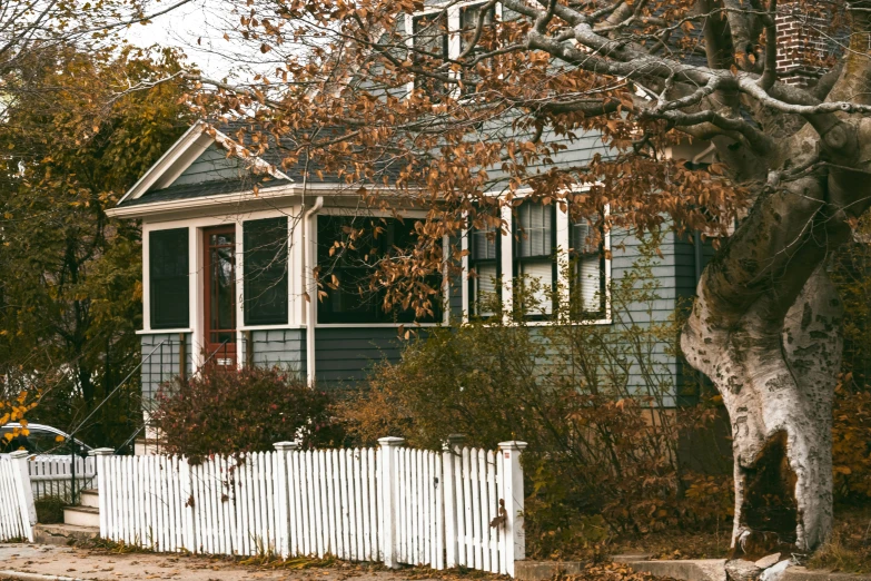 a white fence sits in front of a grey house
