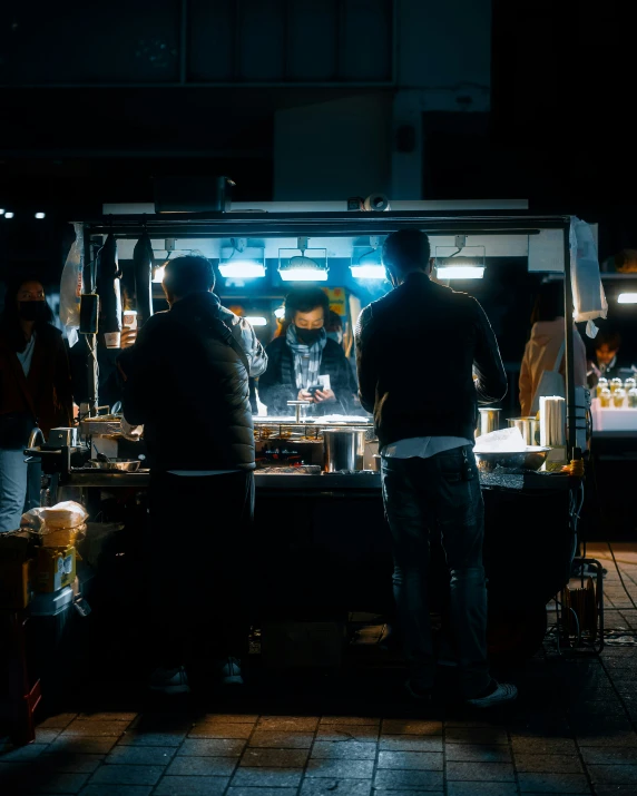 a dark image of a man ordering food from a stand