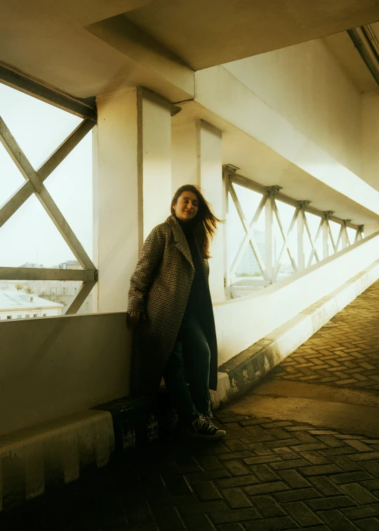 a woman leaning on the side of a wall near some windows