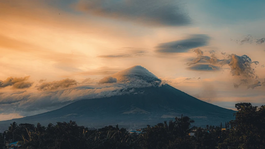 a mountain that is under a very cloudy sky