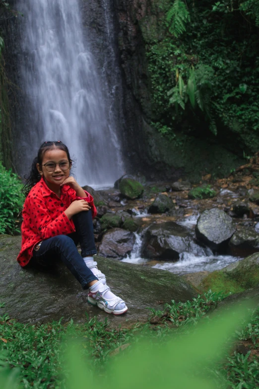 the  is posing in front of the waterfall