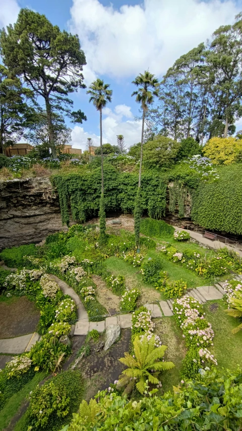 a green landscape is filled with greenery, bushes and stone walls