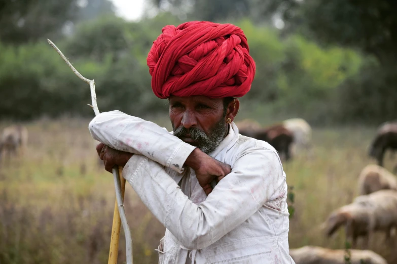a man with a red turban holding a stick