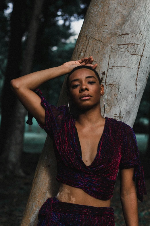 a woman leaning against a tree with her hand on her head