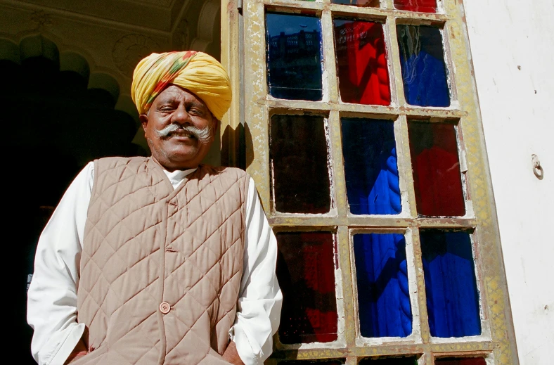 man in a turban standing beside a window