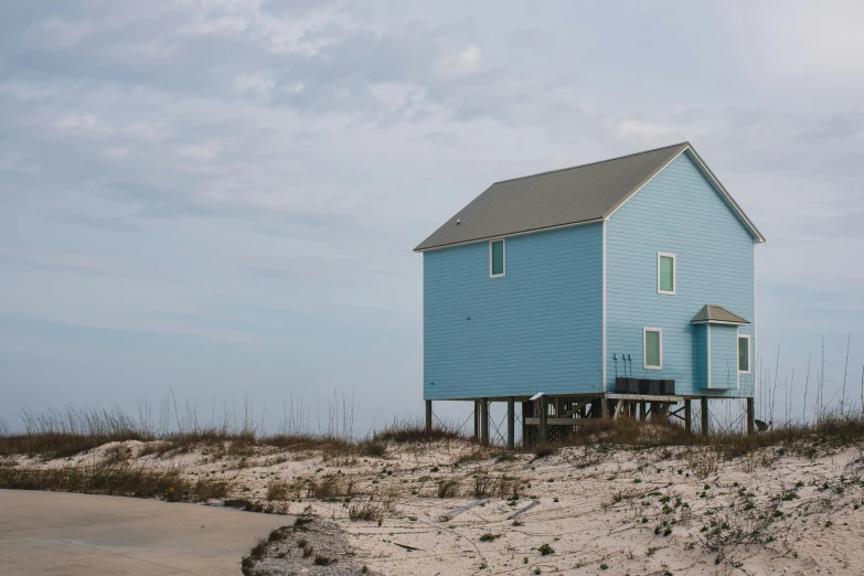 a blue house sitting on top of a sandy beach