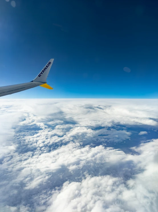 a blue sky over clouds, with an airplane in the distance