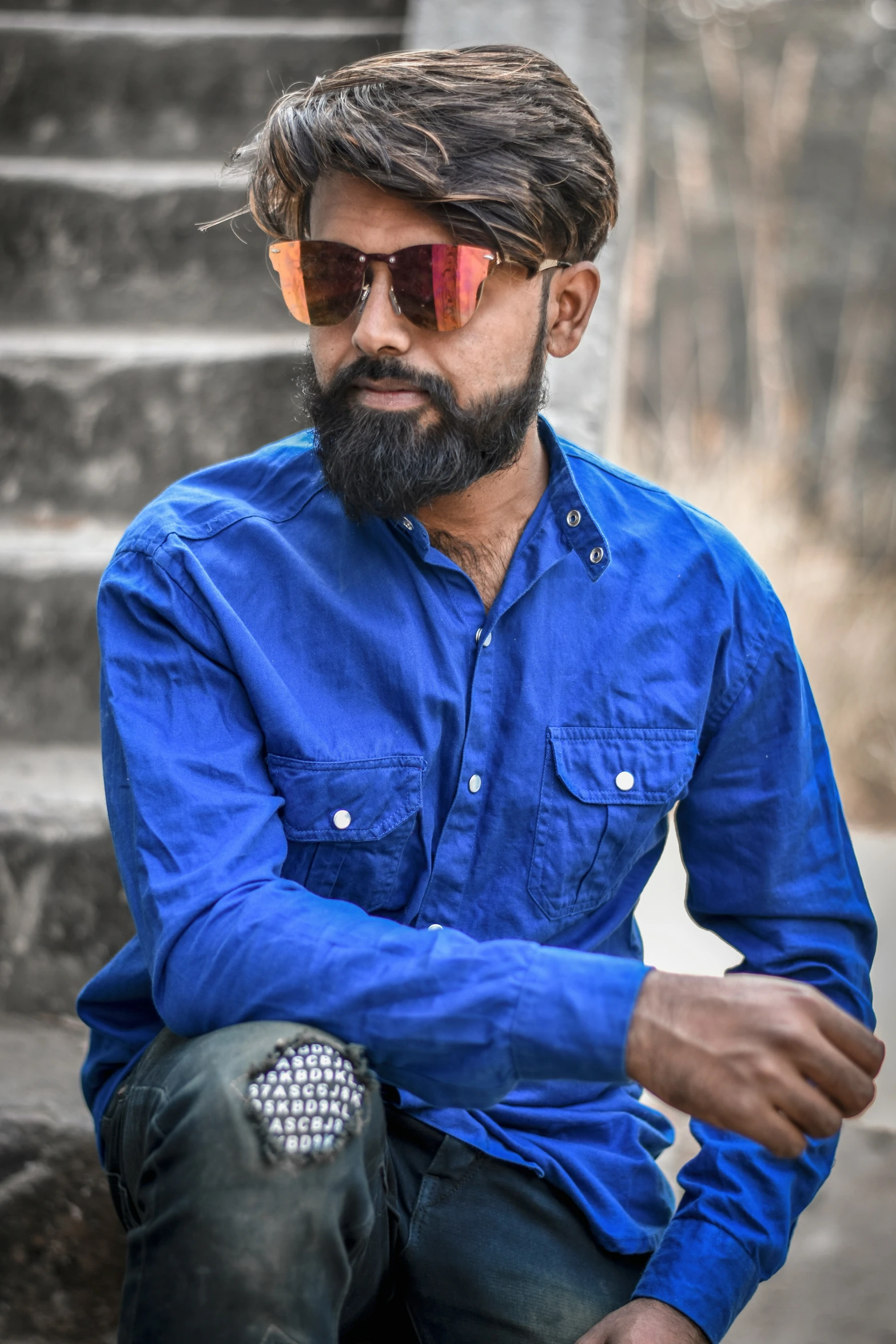 a man in blue shirt and sunglasses sitting on a step