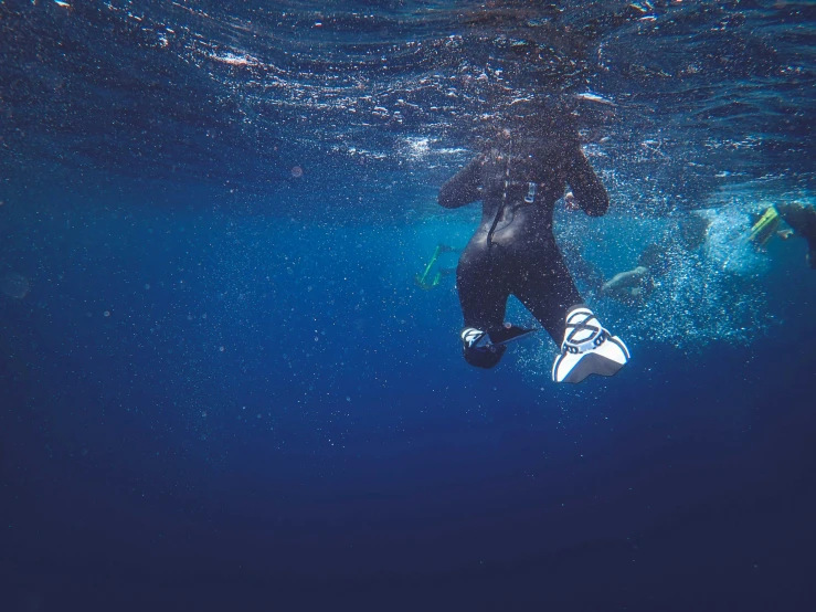 a man under water wearing wetsuit with a flipper under his feet