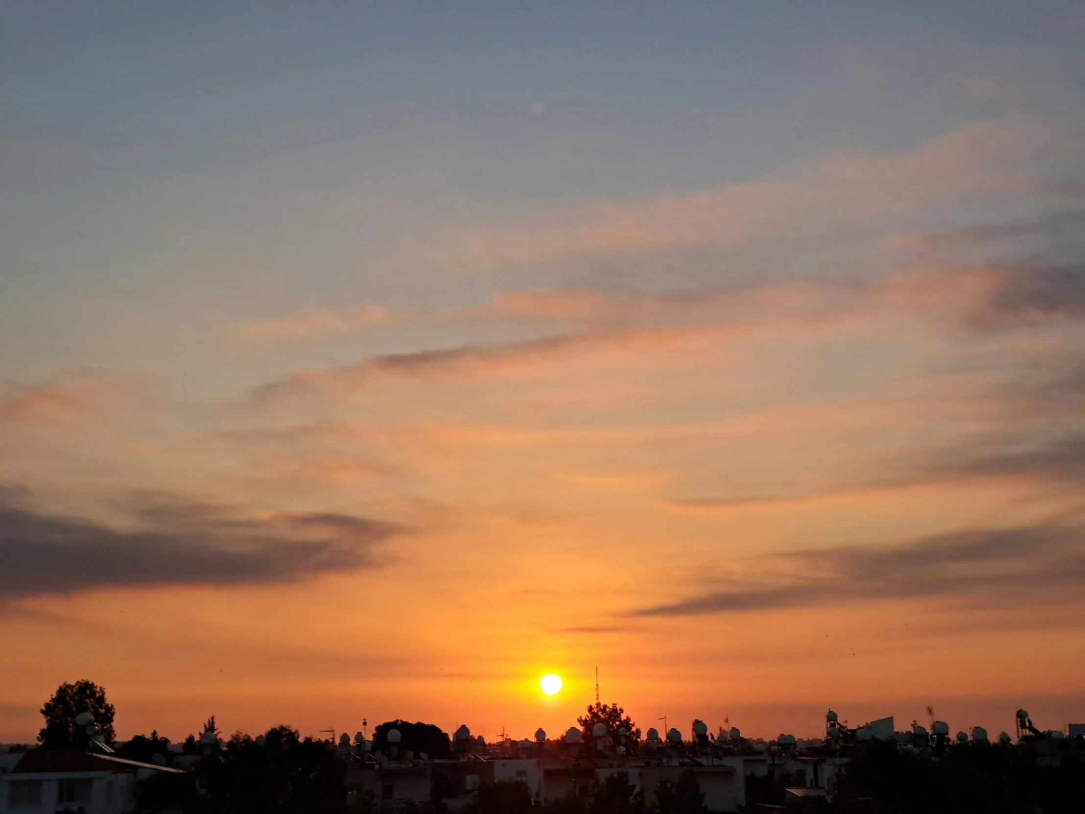 the sun sets over a neighborhood with many houses