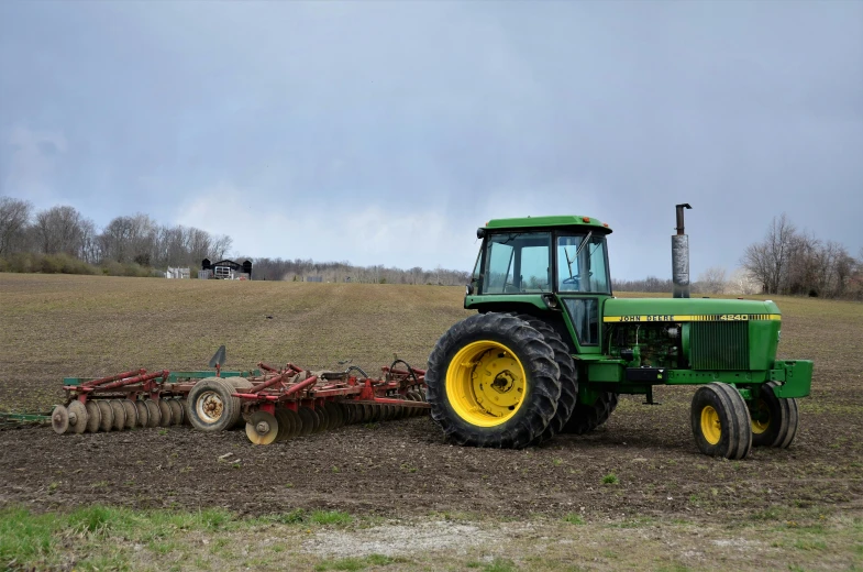 a large green tractor with a plow attached to it