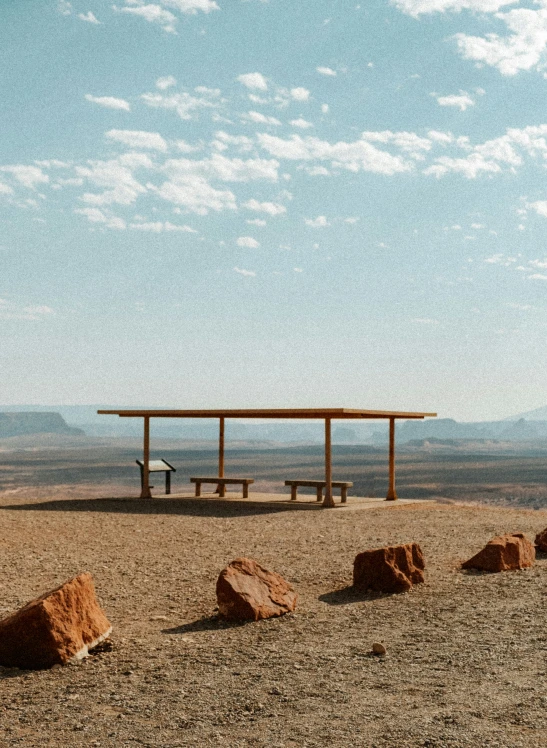 a wooden picnic table with two benches in the desert