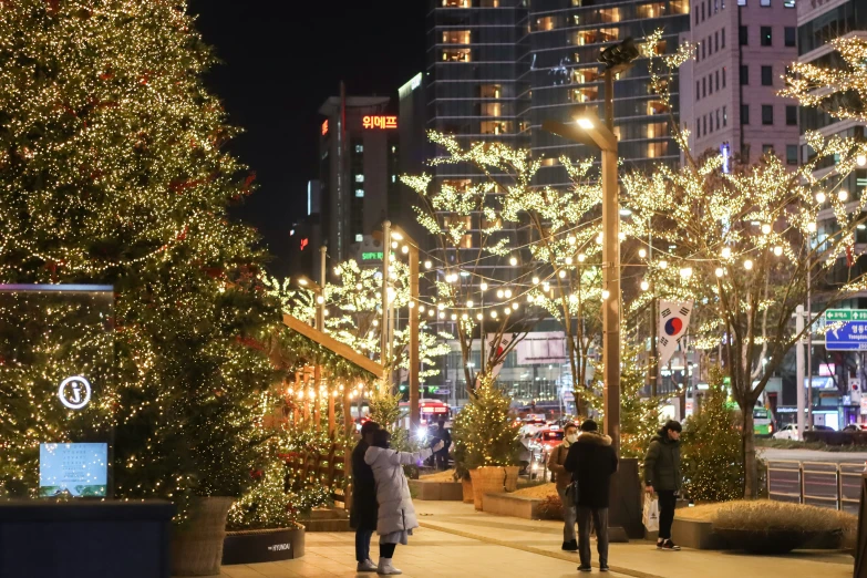 there are people walking down the street with christmas lights on