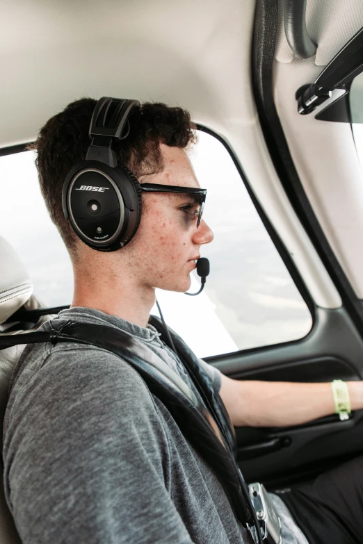 the man sits in the cockpit of a vehicle wearing a headset