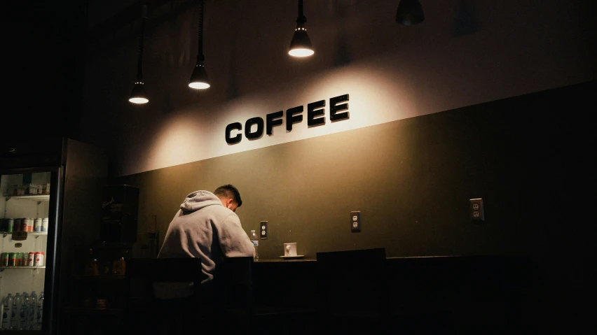 a person behind a coffee shop counter at night