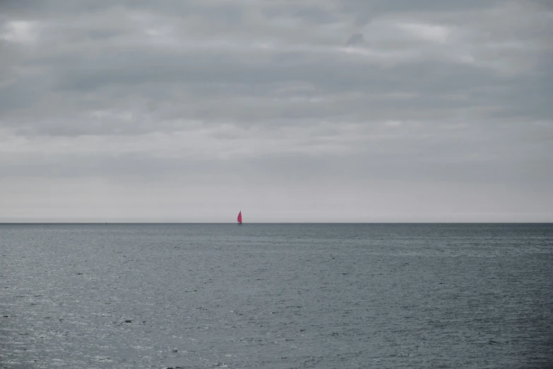 a boat floating on the water under a cloudy sky