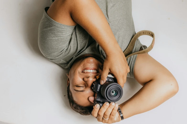 a man lying down holding a camera to his face