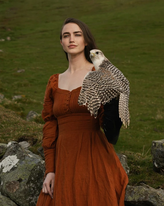 a woman standing next to rocks holding a bird