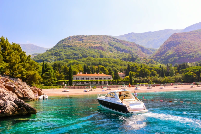 boats glide along the water while mountains surround the beach