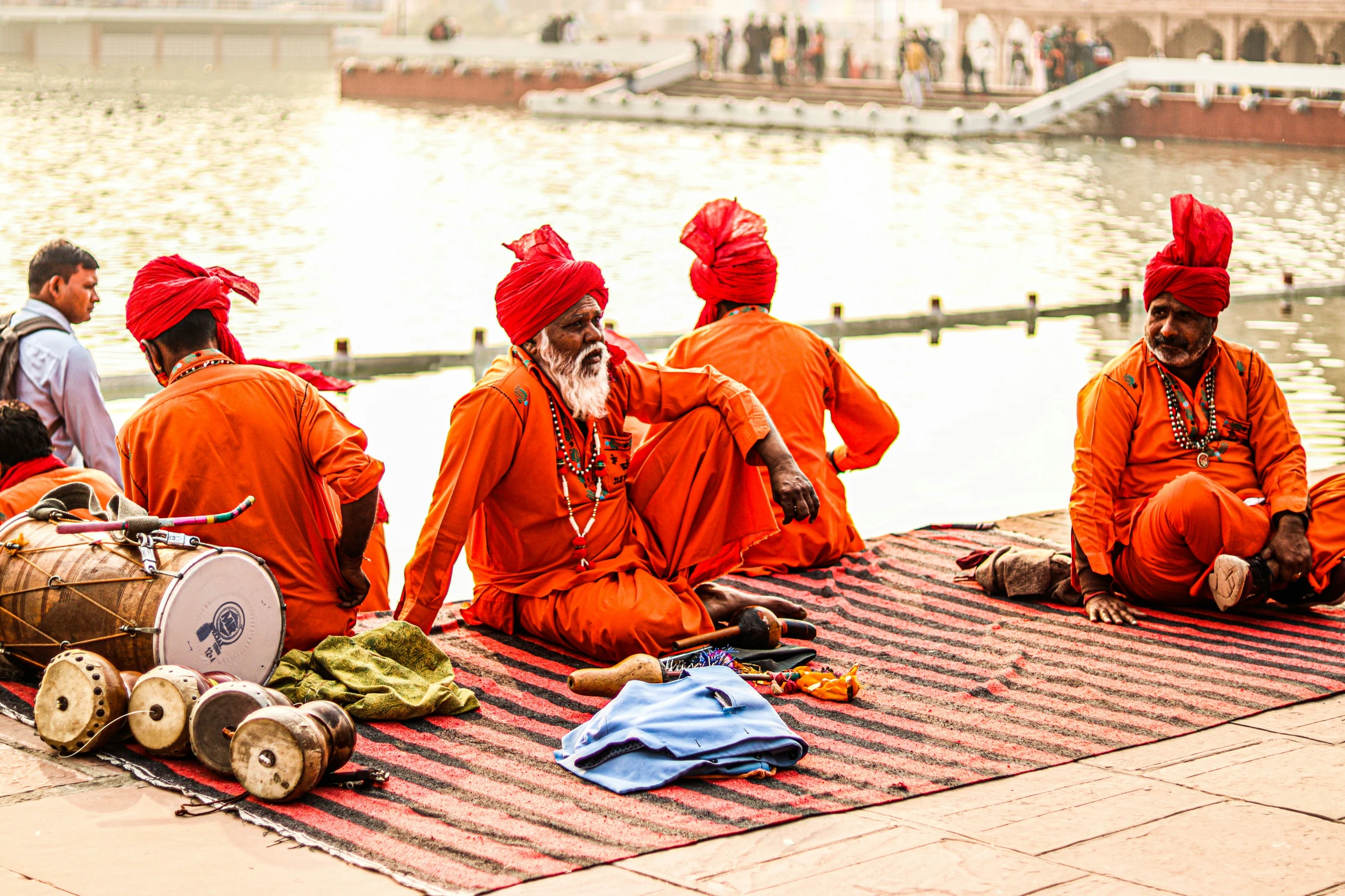 a group of people sitting on a rug near water