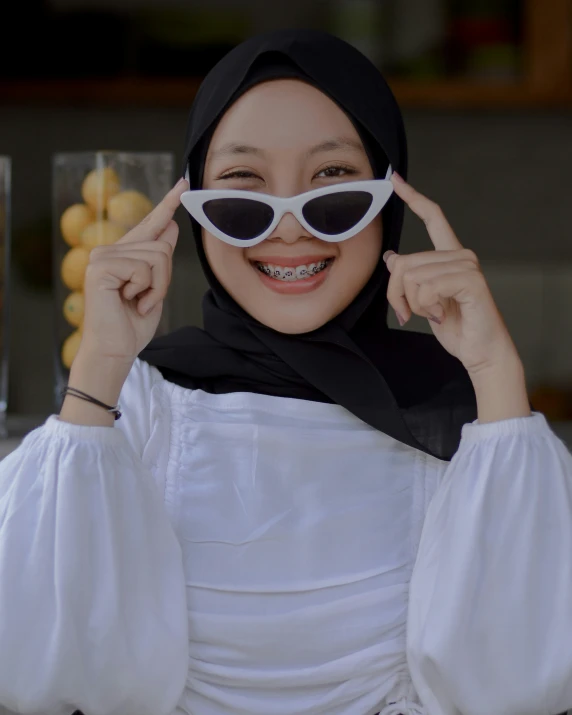 a woman is dressed in white and shows off her sunglasses