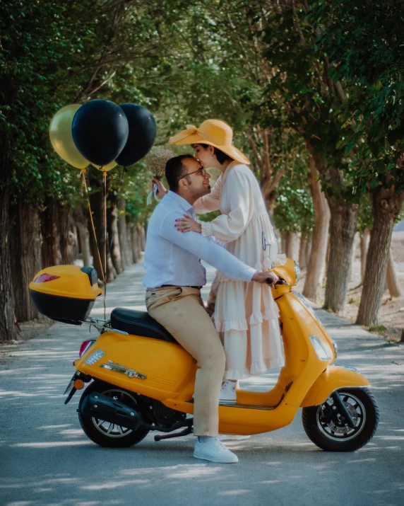 a couple riding a yellow motor scooter