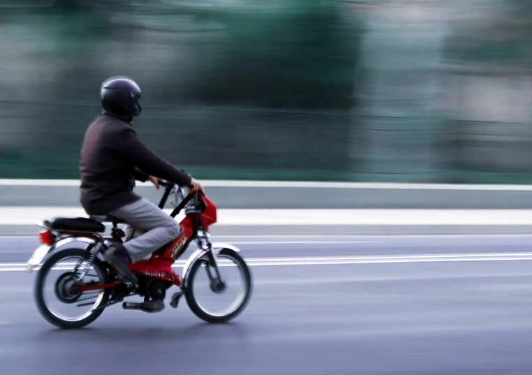 a man wearing grey pants riding a red bike