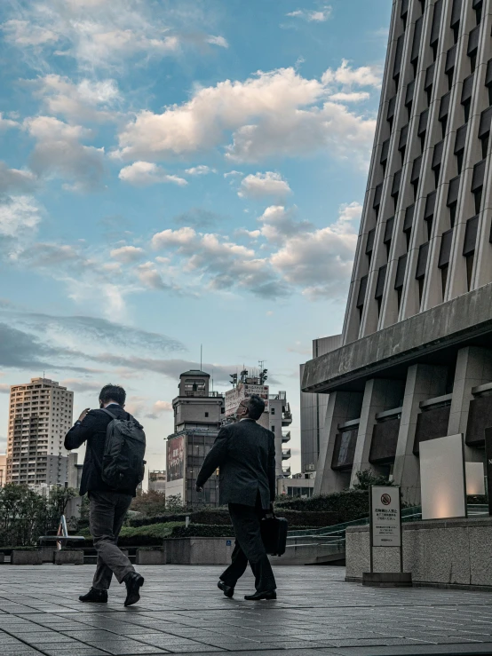 two people walking on a paved pathway in a park