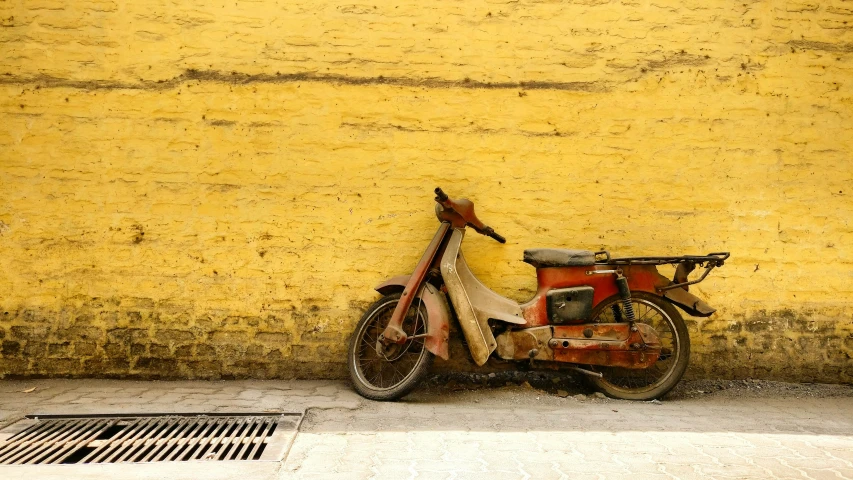 a parked motorcycle and basket in front of a yellow wall